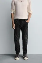 Pantalón de jean azul oscuro con efecto lavado y roturas en las rodillas, de corte ajustado al cuerpo desde la cintura hasta el tobillo.