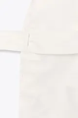 Chaleco largo color blanco, de escote en pico y sin mangas. Tiene bolsillos de vivo en el delantero, aberturas laterales y cinturón multiposición del mismo tejido.