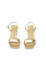 Sandalias doradas de cuero metalizado con tira ancha, pulsera fina ajustable al tobillo y tacón bloque de 5 cm.