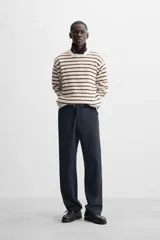 Sweater de punto color crudo con rayas horizontales marrones, de corte relaxed fit, cuello redondo y mangas largas con terminaciones en rib.