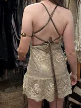 Vestido corto de lentejuelas color verde oliva, con escote en V, breteles finos cruzados en la espalda, cut-outs laterales y volado en el ruedo.