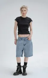 Bermuda de denim azul claro con efecto desgaste, corte oversize y estilo carpintero con bolsillo lateral.