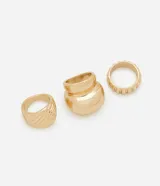 Set de tres anillos dorados con diferentes texturas: uno liso y grueso, uno con textura acanalada y uno con textura de pequeñas muescas.
