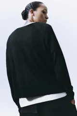 Jersey de punto liso, color azul brillante, con cuello redondo y manga larga. Presenta acabados en rib en puños, cuello y bajo, con aberturas laterales en el ruedo.