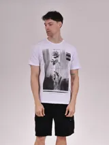 Remera blanca de algodón con estampado rectangular en blanco y negro de una rosa sostenida por una mano tatuada.