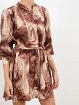 Vestido camisero corto con estampado abstracto en tonos grises, negros y beige. Cuello mao, manga larga con puños abotonados, cintura con lazo y cierre frontal con botones ocultos.