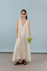 Vestido largo confeccionado en lino de color beige, con escote en V, diseño sin mangas y silueta holgada de caída fluida.