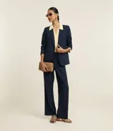 Blazer azul marino de corte sastrero, con solapas con detalle de puntilla en color crema, cierre con un botón dorado y bolsillos delanteros con solapa.