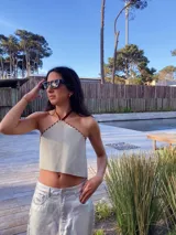 Top corto blanco con escote halter y tiras finas marrones con costuras a la vista.