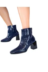Botines de cuero vacuno azul marino con efecto croco brillante. Tienen caña media, cierre lateral y tacón bloque negro brillante de aproximadamente 7 cm.