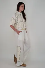 Pantalón blanco de lino con cintura elastizada, cordón de ajuste, bolsillos laterales y apliques de flores bordadas en los laterales.
