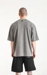 Remera gris melange de corte crop y calce oversize, con hombros caídos y cuello redondo.