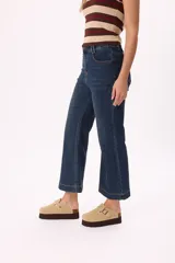 Pantalón jean negro de tiro medio con pierna ancha acampanada y corte cropped.