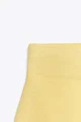 Minifalda amarilla de punto liso, tiro alto, cintura elástica y corte evasé.