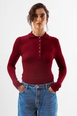 Top de tejido de punto acanalado color negro, de manga larga y cuello polo con botones frontales.