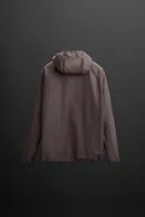 Cazadora con capucha confeccionada en tejido técnico ligero con partículas reflectantes. Cuenta con cuello alto, mangas largas con puños elásticos, bolsillos frontales con cierre de cremallera y cierre frontal con cremallera.