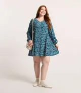 Vestido corto de crepé color verde azulado con estampado de mini corazones blancos, escote en pico, mangas largas con puños elásticos y cierre en la espalda.