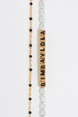 Pulsera dorada de doble cadena, una con perlas y otra con letras negras que forman la marca Bimba y Lola.