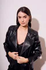 Campera negra estilo biker confeccionada en cuero vegano, con cuello solapa, cierre asimétrico y bolsillos con cremallera.