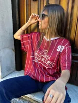 Remerón negro con estampado de rayas verticales blancas y logo de equipo de béisbol en el frente.