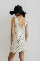 Vestido corto color crema con estampado de lunares negros, escote en V y sin mangas.