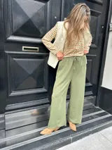 Pantalón verde de seda opaca, corte ancho y fluido, tiro medio alto y elástico en la cintura.