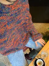 Sweater tejido a mano en lana color gris jaspeado, de calce holgado, con cuello a la base y puños ajustados.