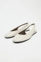 Zapato tipo bailarina destalonada en color crema, con detalle de pespunte en el corte, tira trasera con pieza elástica y acabado en punta redonda.