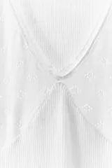 Musculosa blanca de algodón con escote en V y tirantes anchos. Tejido de punto calado en la parte superior y tejido de punto acanalado en la parte inferior.