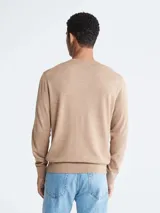 Sweater de lana merino color beige, con cuello redondo y logo bordado en el pecho.