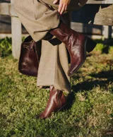 Bota corta color crema con textura de reptil, caña media, punta cuadrada, cierre lateral y taco de madera.