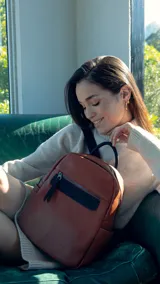Mochila marrón de símil cuero con bolsillo frontal grande, asa de mano y correas regulables en galón.