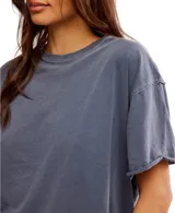 Remera gris de corte cuadrado, ligeramente extragrande, con escote redondo, hombros caídos y costuras sin rematar.