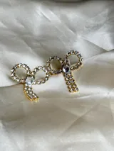 Par de aros colgantes con forma de moño, con engarce de strass y gancho de acero quirúrgico.