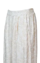 Pantalón largo de playa con estampado floral en tonos naranja, marrón y verde sobre fondo blanco. Confeccionado en tejido ligero y fluido.