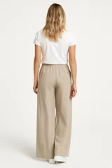 Pantalón de lino color beige, de corte ancho y tiro alto, con bolsillos laterales y cintura elastizada con cordón ajustable.