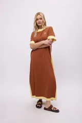 Vestido largo de algodón, color rojo, con cuello redondo y ribetes en color crema en cuello, puños y ruedo. Presenta un pequeño bordado en el pecho.