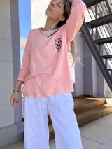 Remera manga larga color salmón con cuello redondo y bolsillo con estampado animal print.