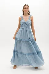 Vestido largo celeste de gasa de algodón con textura liviana. Tiene escote en V con nudo central, breteles con voladitos y frunces en la falda.