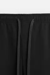 Pantalón de jogging color beige confeccionado en tejido de mezcla de algodón. Cuenta con cintura elástica ajustable con cordón, bolsillos frontales y traseros.