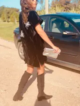 Vestido corto negro de terciopelo con bordado de flores blancas en la espalda, escote en V y corte holgado.