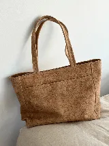 Bolso tipo tote de cuero color tostado, con doble asa de hombro, bolsillo externo y logo de la marca grabado en el frente.