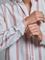 Camisa de lino blanca con rayas verticales color rosa, de manga larga y corte clásico.