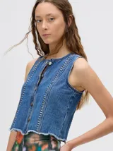 Chaleco de denim celeste con apliques metálicos y flecos en el ruedo.