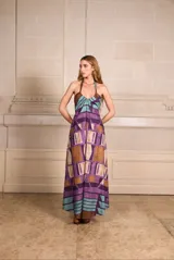 Vestido largo con estampado geométrico en tonos violeta, marrón y celeste, con cuello halter y espalda descubierta.