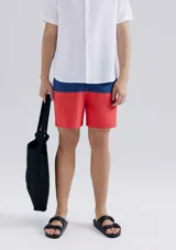 Shorts de baño con diseño bicolor, azul en la cintura y rojo en la parte inferior. Cuenta con cintura elástica y cordón ajustable.