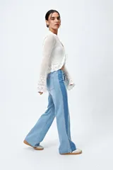 Pantalón de jean celeste con corte recto, tiro medio y pierna ancha. Presenta un recorte lateral en tono azul oscuro.