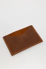 Tarjetero de cuero marrón con costuras en los bordes y logo de la marca SierraMora grabado en el frente. Tiene ranuras para tarjetas en ambos lados.
