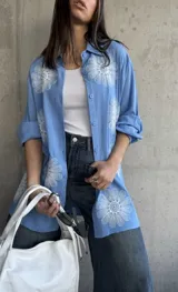 Camisa celeste de manga larga con bordados de flores blancas.
