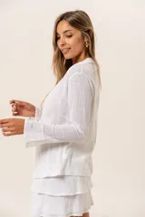Blusa blanca de manga larga con cuello camisero y lazo en la cintura.
